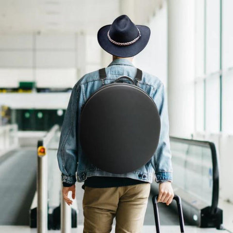 man in airport with hat case on his back