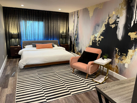 Modern bedroom concept with pattern rug, king bed and luxury abstract wallpaper mural featuring black, blush and gold.