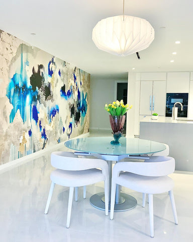 Modern kitchen with glass kitchen table, island and large abstract wallpaper mural featuring blues, golds, silvers and black tones.