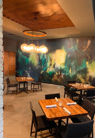 Restaurant interior design concept with green, black and gold abstract wallpaper mural on the back wall. Wallpaper murals create a great feature piece of art in restaurants or other commercial spaces.