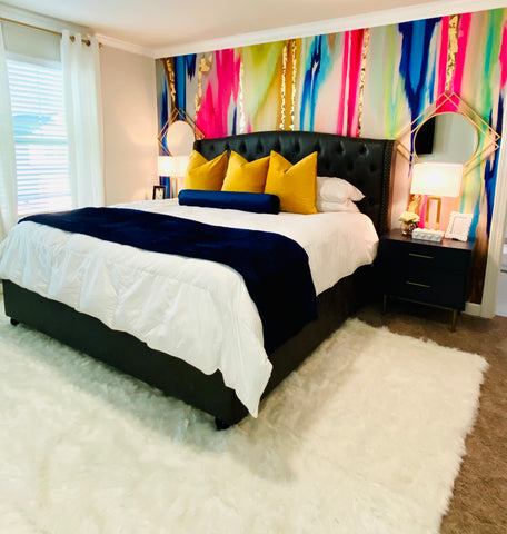 Colorful teen bedroom with black and white bedding and brightly colored wallpaper mural on feature wall.