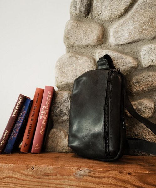 black leather sling bag sitting on shelf