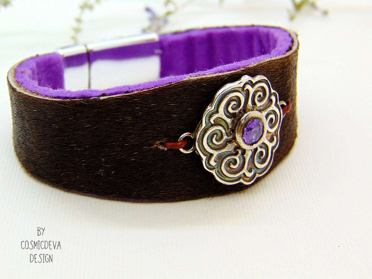 One of a kind handcrafted leather cuff bracelet made of hand cut earthy brown hair on cowhide leather. The focal point is a purple cubic zirconia amethyst in a bezel setting on a Celtic design textured solid 950 sterling silver disc. The inside of the leather bracelet is lined light purple/ lilac felt for your comfort. The handmade bracelet has silver colored stainless steel magnetic clasp which makes it easy to open and close.
