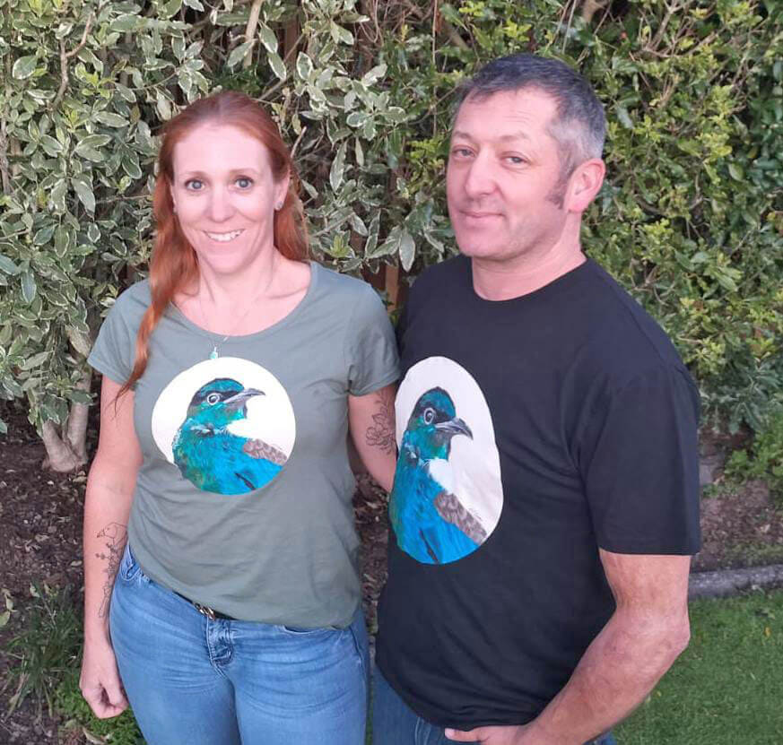 Trish and her husband wearing doodlewear 'Tui Portrait' (2021) art print t shirt by NZ Contemporary Realism Artist Trish Harding