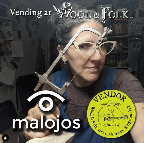 "Vending at Wool & Folk. Malojos" Natalia, wearing white cat-eye glasses, peering through her saw frame.