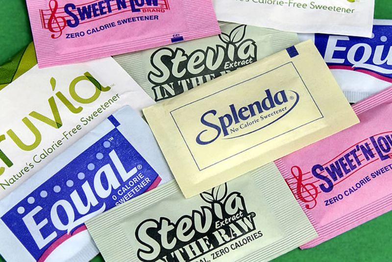 several types of sweeteners laid out on a table including stevia, splenda, sweet'n low