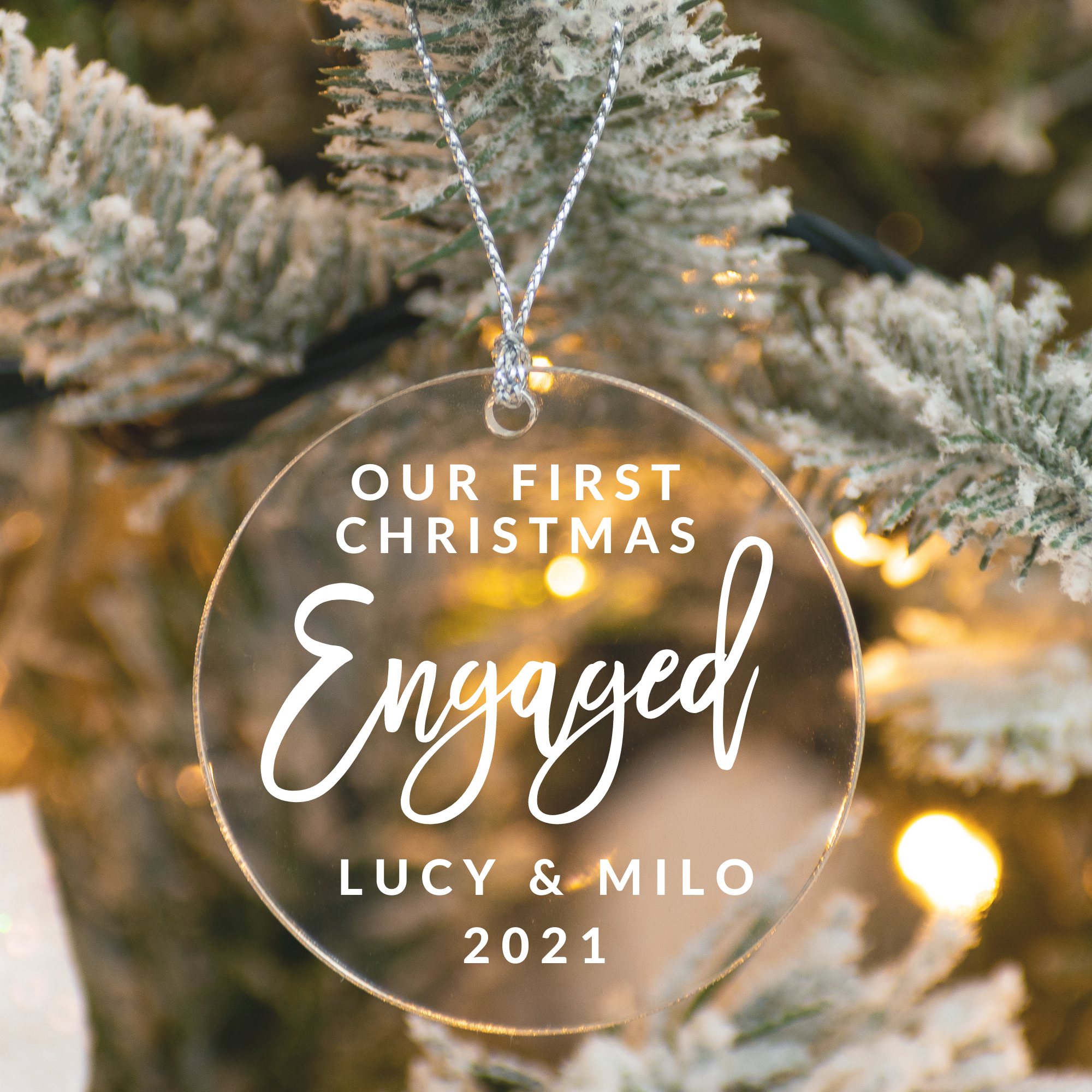 Clear flat ornament with white font that says "Our First Christmas Engaged Lucy & Milo 2021".