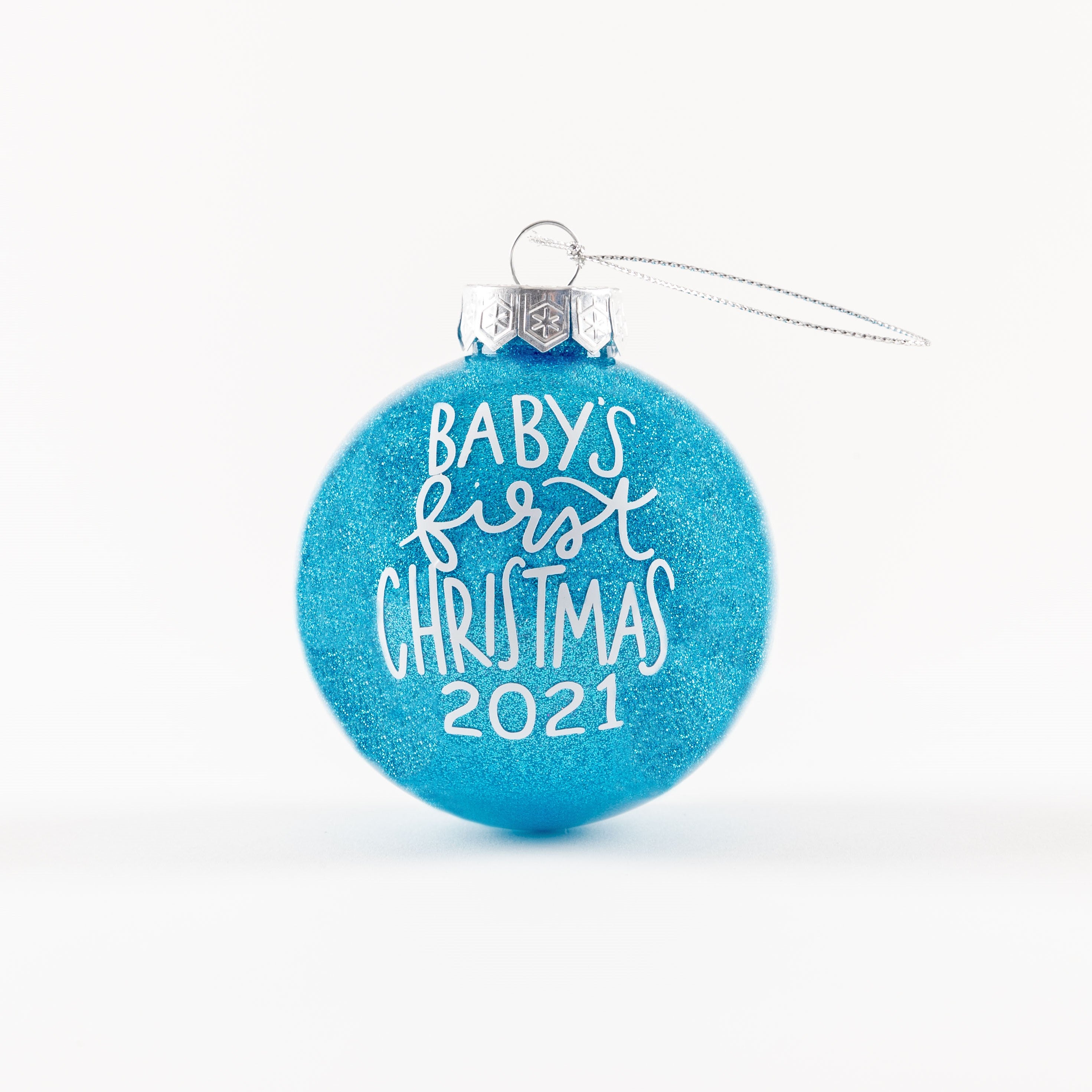 Sparkly blue ornament with Baby's First Christmas 2021 written in white font.
