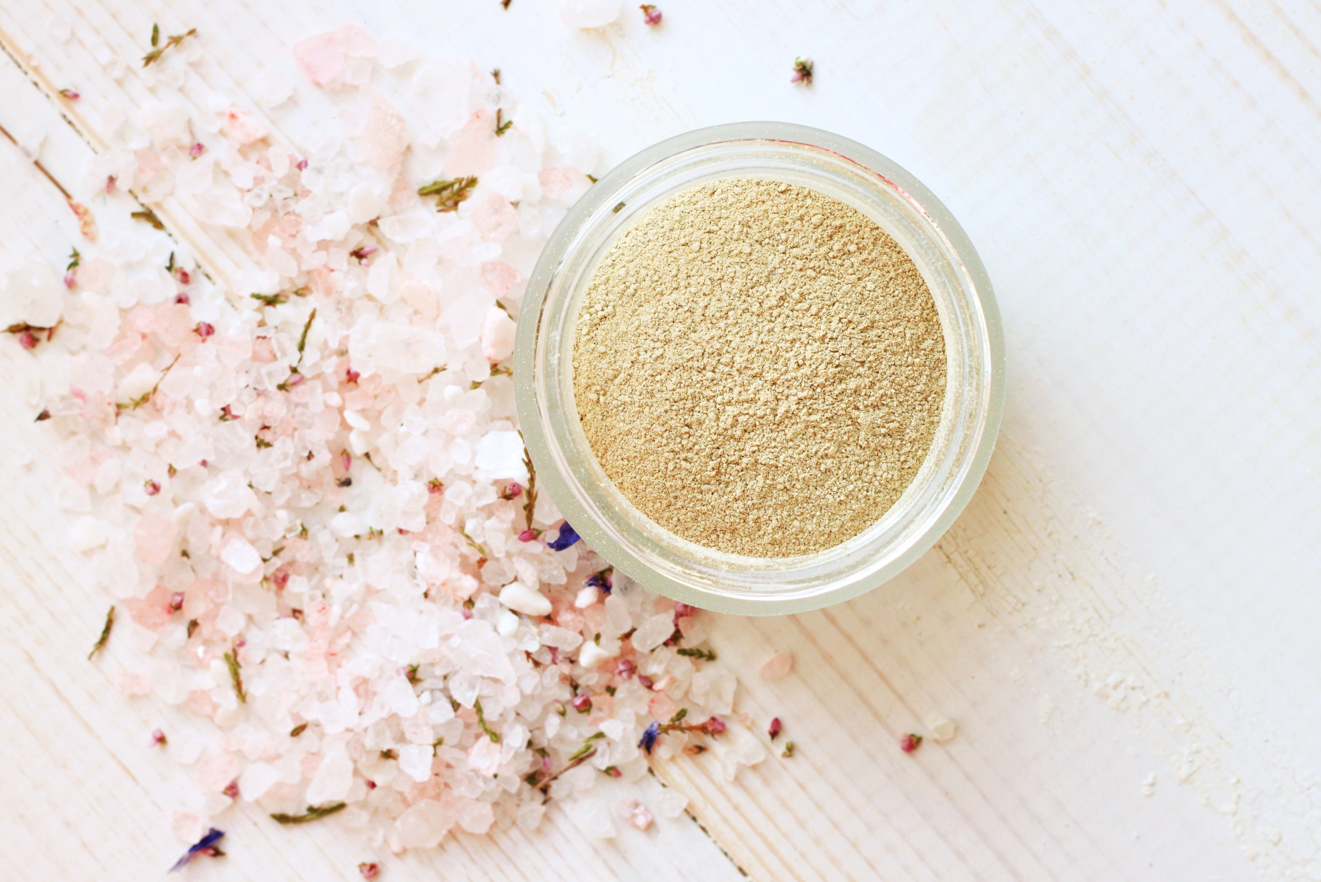 Open jar of clay mask powder next to a pile of bath salts.