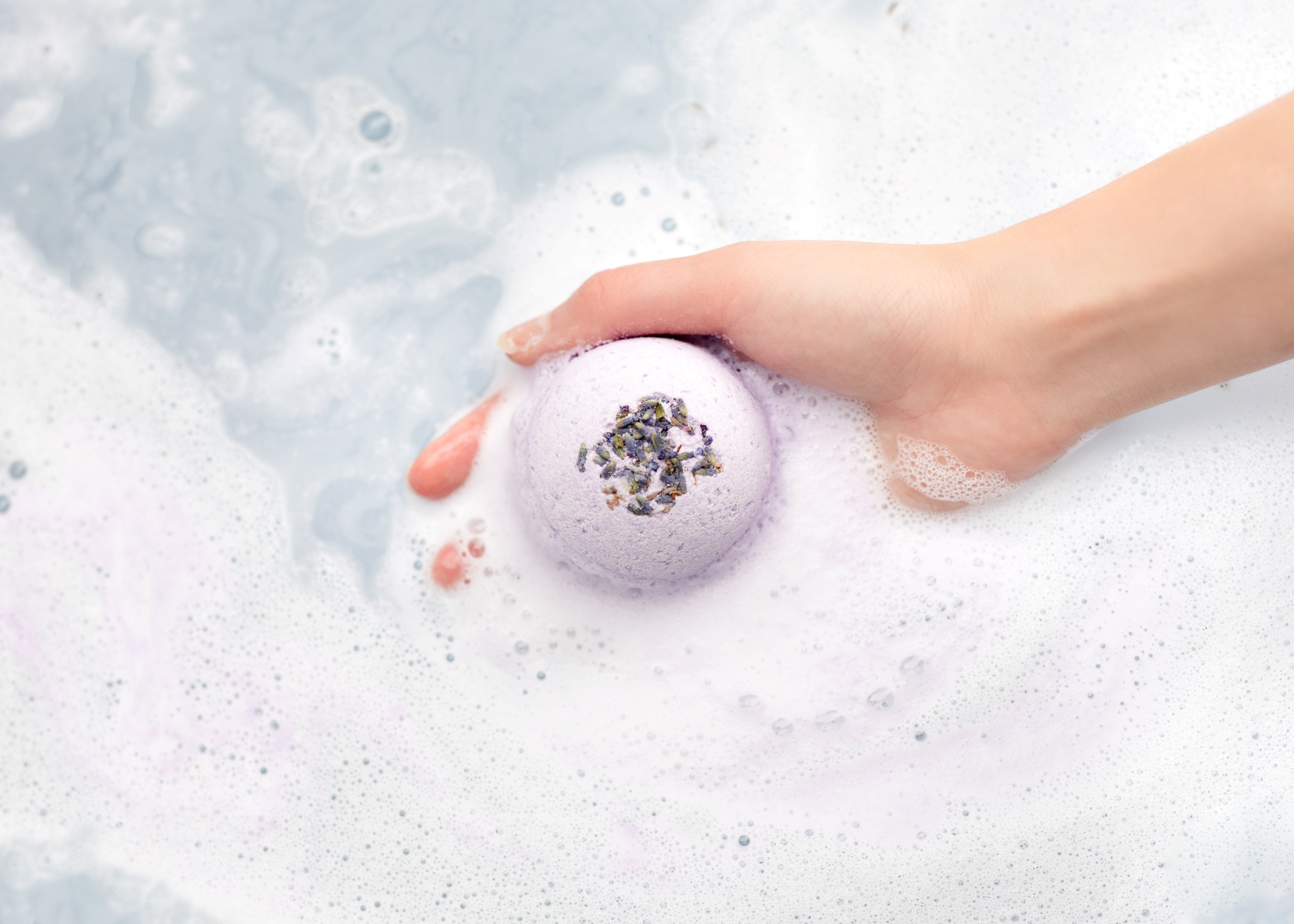 Lavender Bath Bomb being dropped into water.