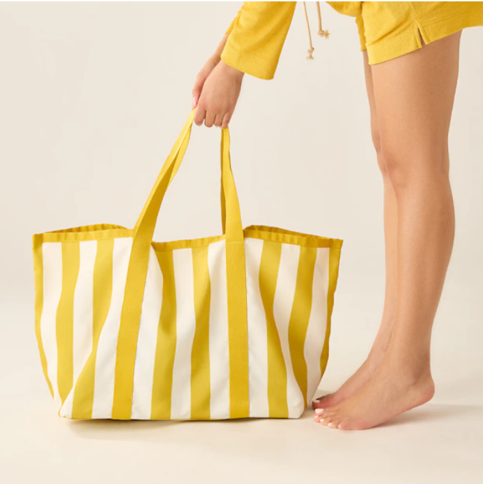 Yellow and white striped tote bag being picked up.