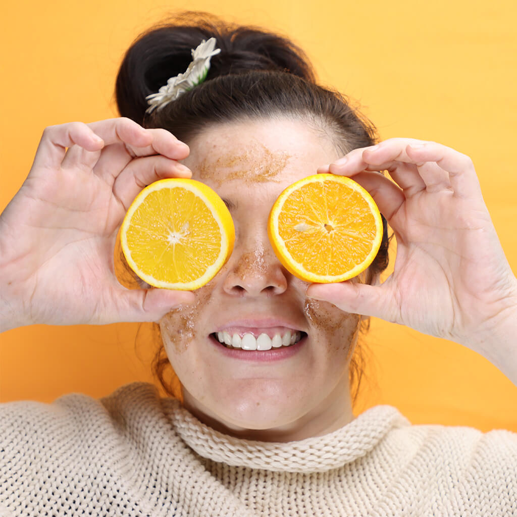 Woman holding sliced orange halves as eyes