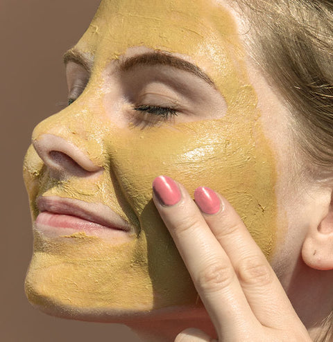 Young woman with face mask applied on her face