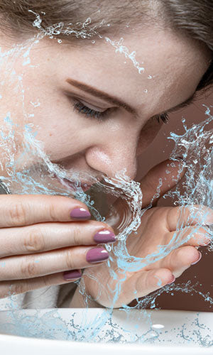 Woman cleaning her face with water