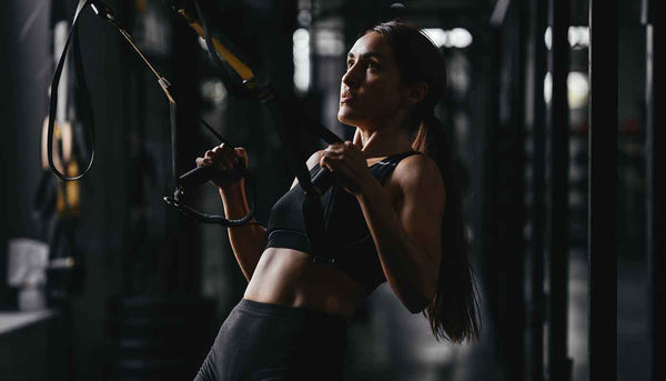 fit woman at the gym in low light gym lifting weights and exercising