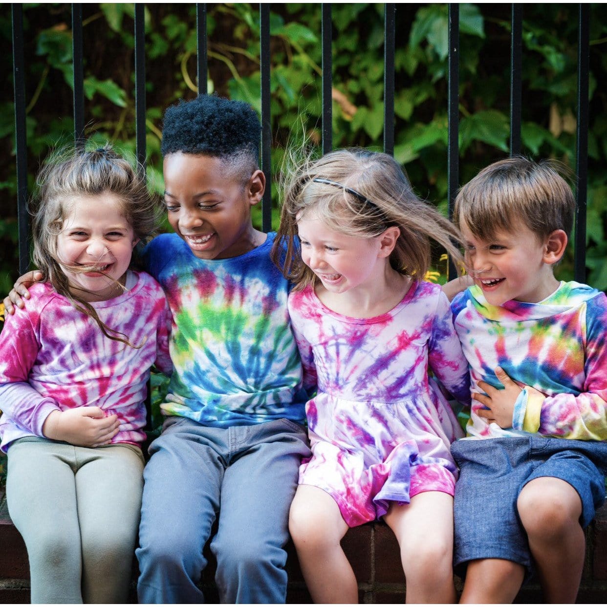 Four kids wearing kids tie dye clothing. 