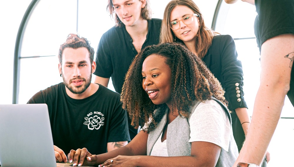 A small, diverse group of coworkers looking at a laptop