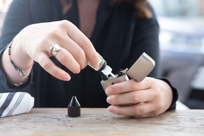 close up of woman’s hands filling tank of pod vape