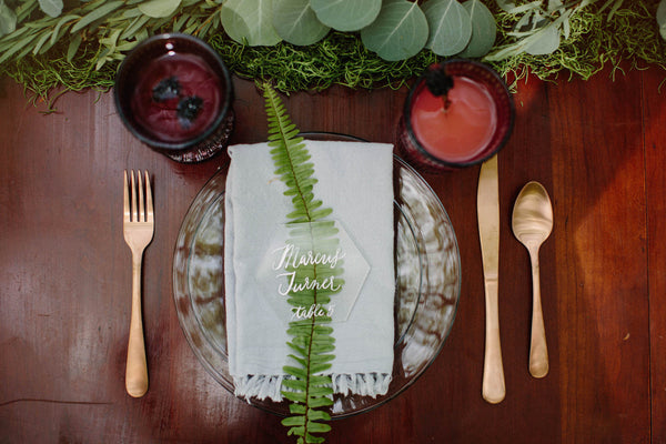 A wedding place setting with fern and lucite place cards