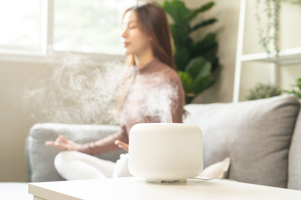 woman meditating with a essential oil diffuser