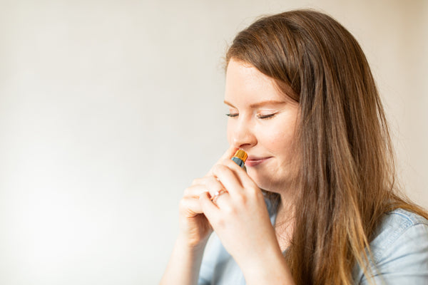 woman inhaling essential oils for wellness from an essential oils inhaler