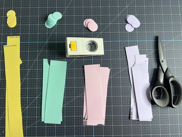 making paper confetti with pink, yellow and purple paper scraps