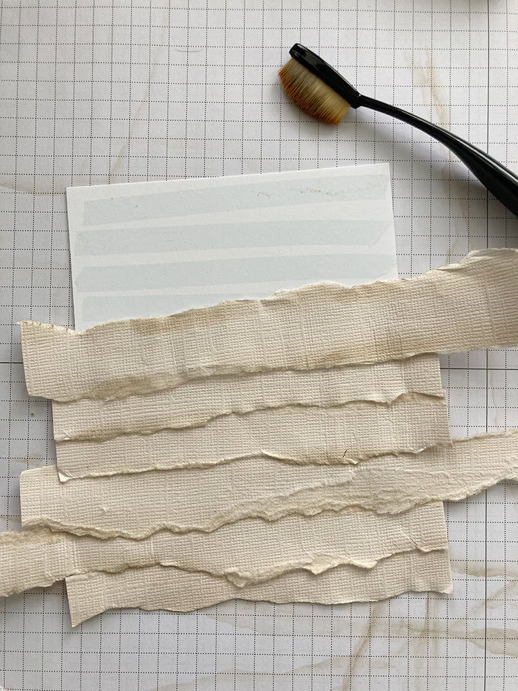layered strips of torn paper placed on a white paper background to make a mummy card