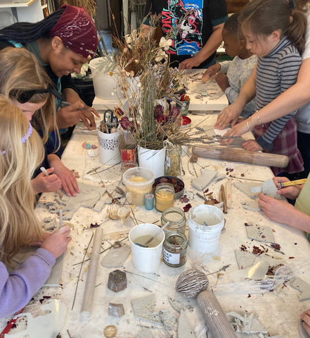 Children and adults making ceramics at a table