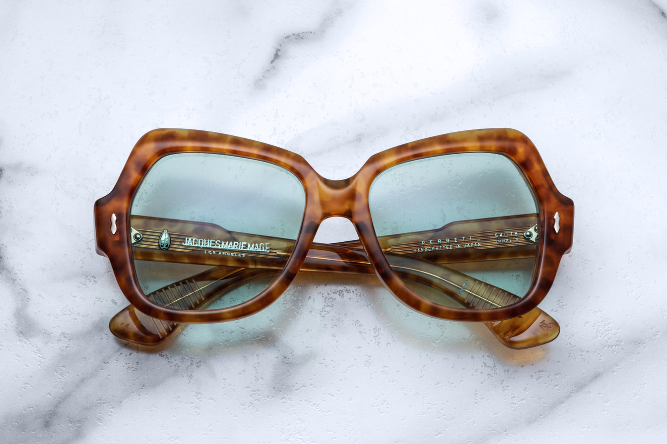 Oversized Havana pattern sunglasses frame lying folded on white marble surface