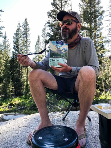 Man having snacks in a camping trip journal entry Selkbag