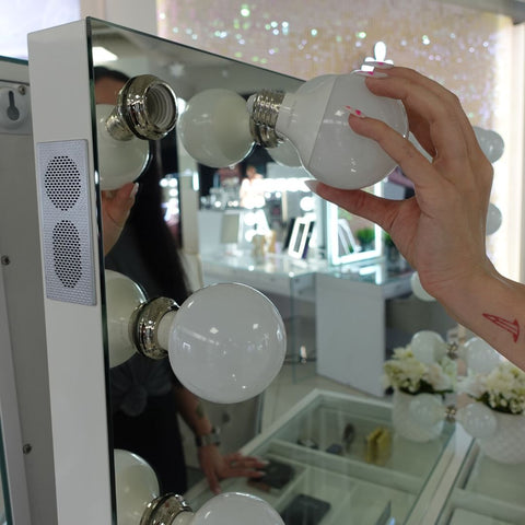 a woman removing bulbs from the Hollywood Vanity Mirror – IVC