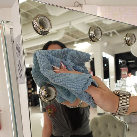 a woman wipes the Hollywood Vanity Mirror with a microfiber cloth – IVC