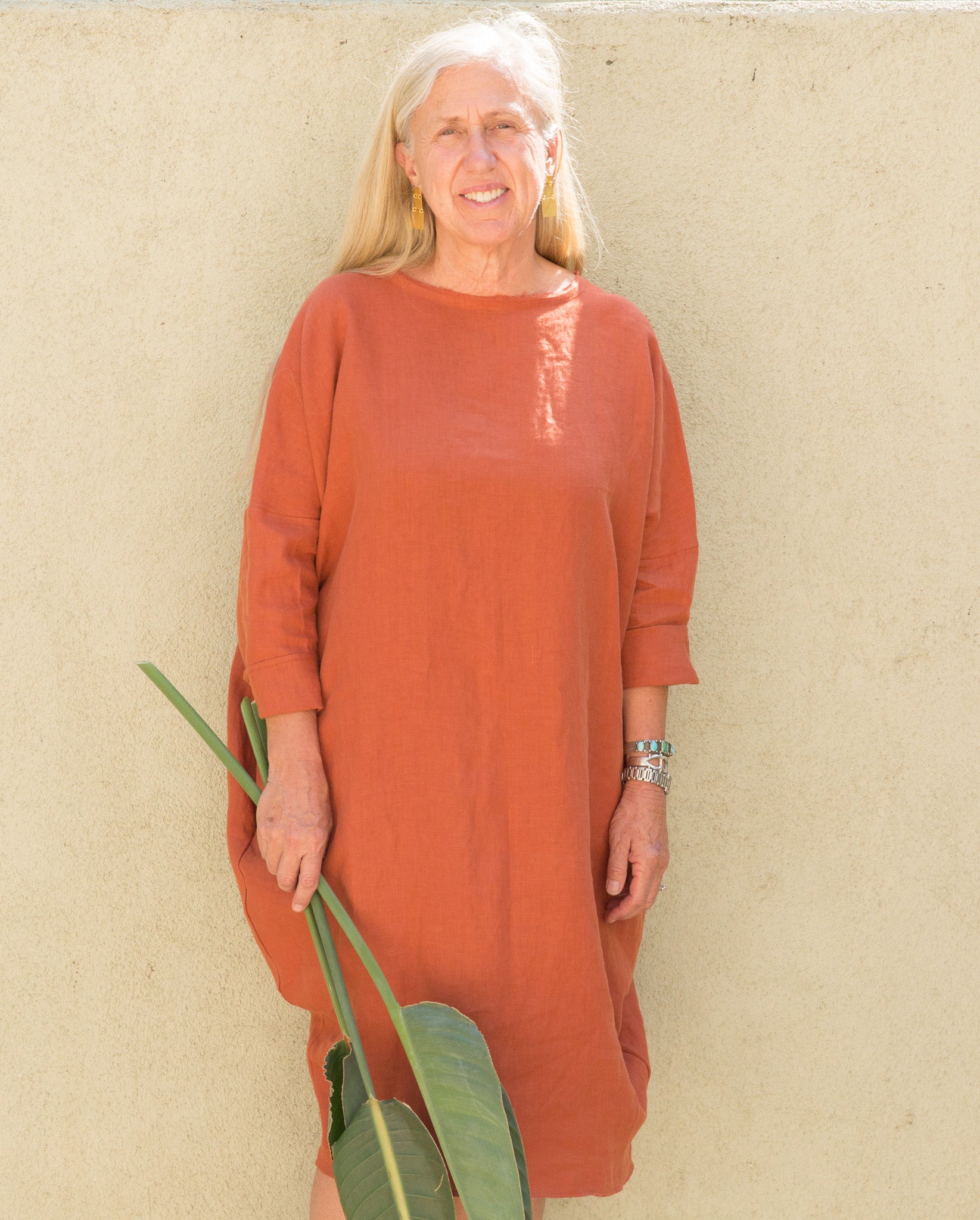 Susanne McLean wearing a Robyn King dress in front of green wall