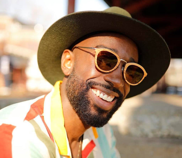 black man wearing bamboo sunglasses and smiling