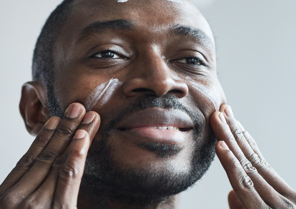 Black man applying sunscreen to his face