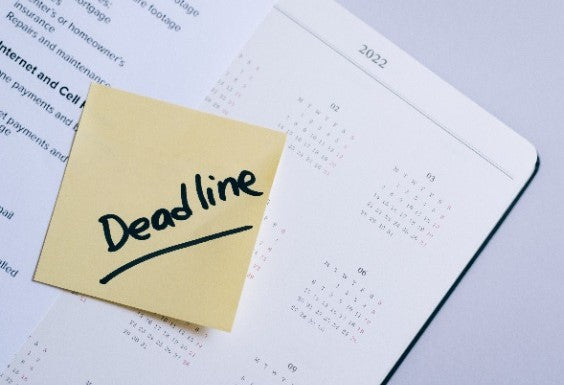 yellow sticky note on calendar with "deadline" written on it