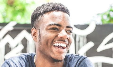 Afrocenchix how to care for men';s curly and afro hair care article: Young black man with short black hair smiling