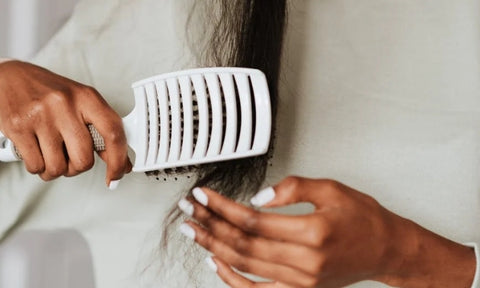 Afrocenchix how to detangle your natural hair: close up of a black woman detangling her hair with a brush