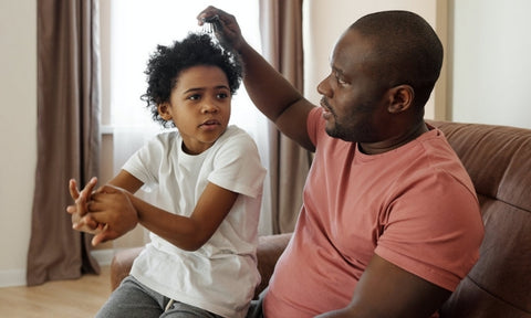 Afrocenchix how to detangle your natural hair: father and child sitting together detangling and combing curly afro hair
