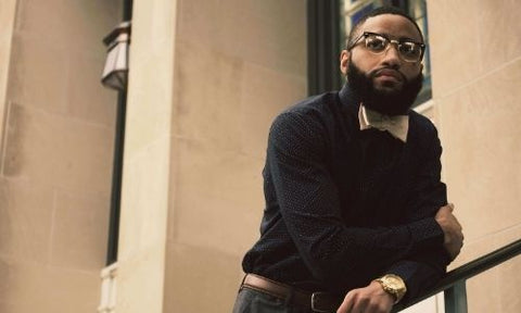 Black man leaning on a rail with a Garibaldi beard and glasses