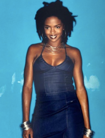 Lauryn Hill smiling with dreaklocks wearing a denim outfit