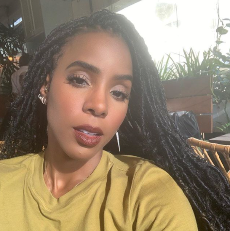 Kelly Rowland with faux locs wearing a mustard top