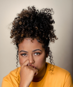 Black woman wearing a yellow top with pineapple hairstyle looking fed up