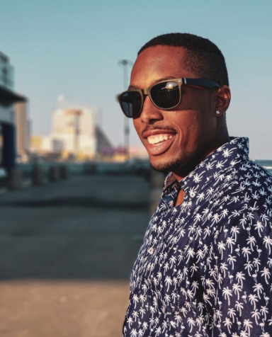 Black man with short buzz cut smiling with sunglasses