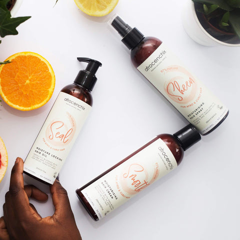 A hand touching the Afrocenchix moisture surge set with citrus fruit