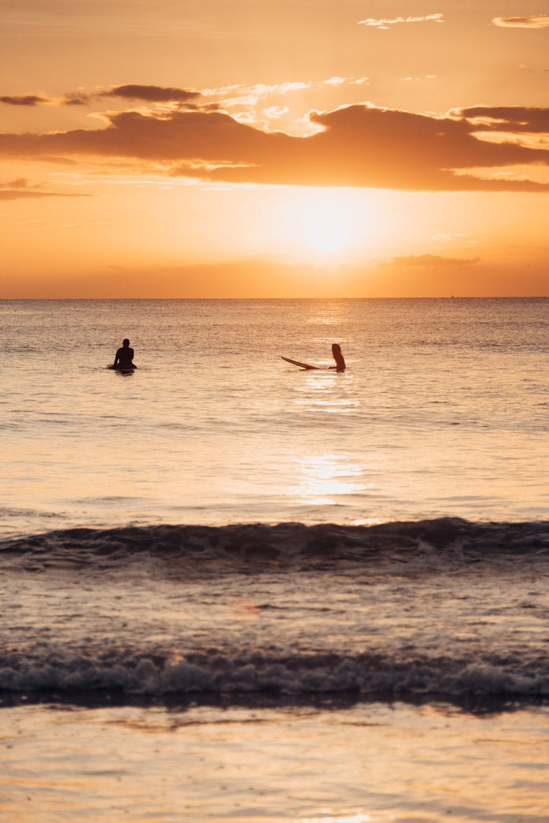 Surfers sitting in the ocean in Tamarindo Costa Rica. Photographed by Kristen M. Brown, Samba to the Sea for The Sunset Shop.