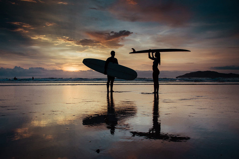 Endless Summer sunset in Tamarindo Costa Rica. Surfer silhouettes during sunset. Surfers holding their surfboards on the beach during sunset in Tamarindo. Photographed by Kristen M. Brown, Samba to the Sea.