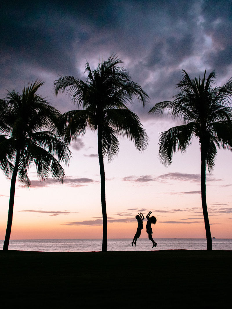 Siblings high fiving at sunset in Playa Flamingo Costa Rica. Sunset art pictures photographed by Kristen M. Brown, Samba to the Sea for The Sunset Shop.