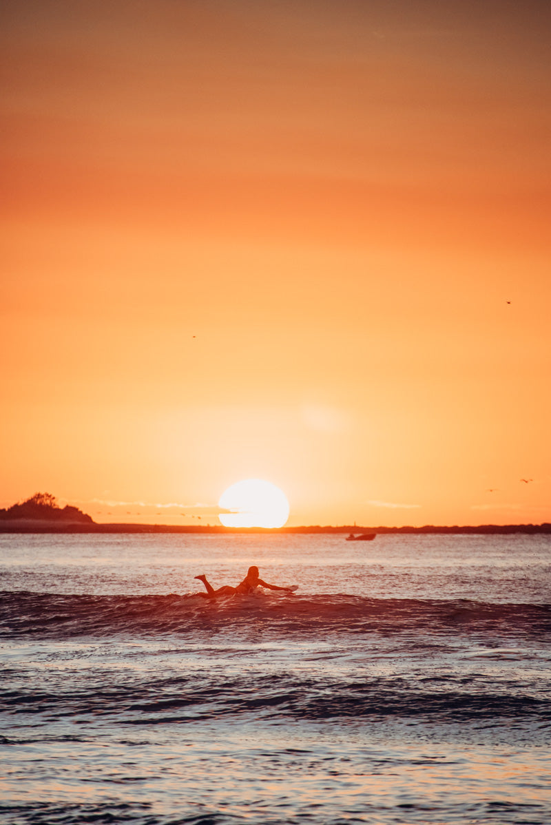 Female surfer during sunset in Tamarindo Costa Rica during sunset. Photographed by Kristen M. Brown, Samba to the Sea for The Sunset Shop.