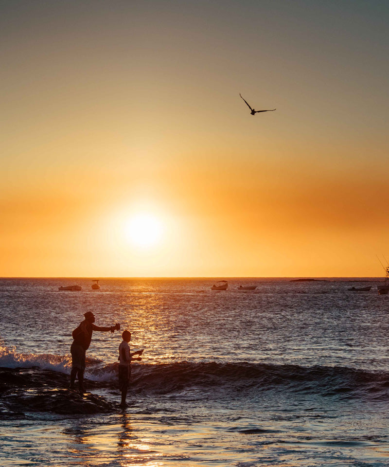 Father and son fishing during sunset in Tamarindo Costa Rica. Sunset art pictures photographed by Kristen M. Brown, Samba to the Sea for The Sunset Shop.